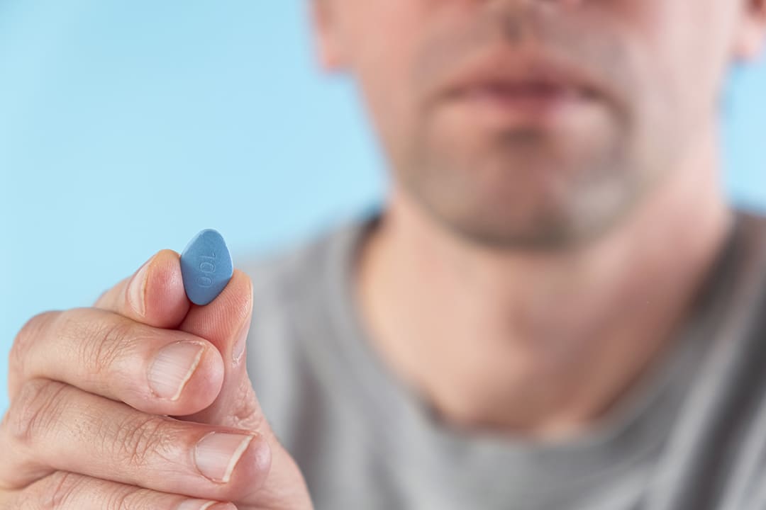 man holding blue pill for ED