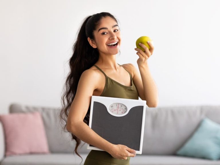 Lady holding scale and apple to illustrate taking semaglutide to suppress appetite