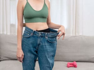 woman showing weight loss via size of jeans to illustrate best protein sources to power your diet