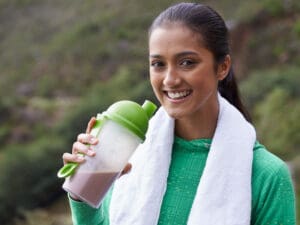 young smiling ethnic woman holding a protein shake