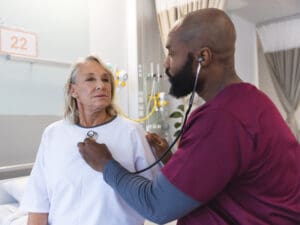 African-American male doctor examining an older female patient to illustrate checking how aging affects immunity