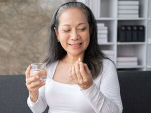 happy elderly woman taking a pill to help her age healthily