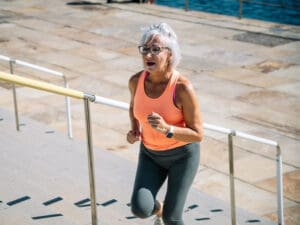 older woman in sports clothing running up steps to illustrate how to reduce age-related inflammation