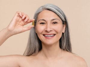 happy woman holding a pill as she considers the aging process