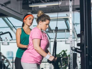 trainer helping overweight woman in the gym to illustrate healthy habits for weight loss