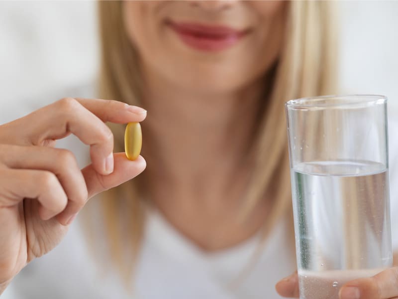 woman holding a tablet and a glass of water to illustrate best menopause supplements for weight loss