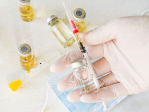 Doctor holding syringe plus bottles to illustrate benefits of vitamin injections