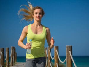 Energise woman jogging on beach to illustrate the energy boost after vitamin shots