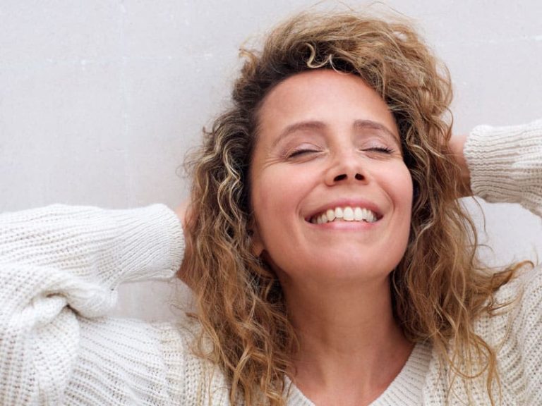 Woman leaning back happily, hands behind head, to illustrate benefits of hormone replacement therapy for menopause